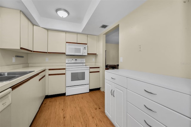 kitchen featuring cream cabinets, white appliances, visible vents, light countertops, and light wood-type flooring