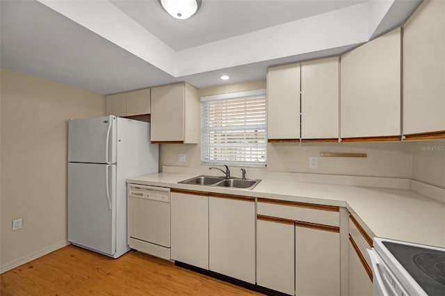 kitchen featuring cream cabinets, white appliances, a sink, light countertops, and light wood finished floors