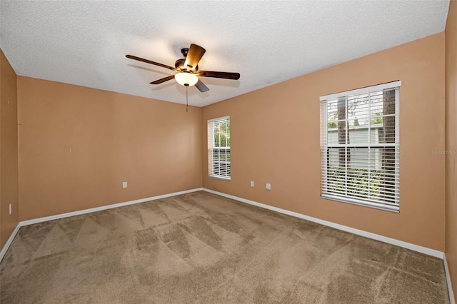 carpeted empty room with ceiling fan, a textured ceiling, and baseboards