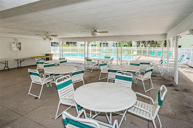 view of patio / terrace with a community pool, fence, a ceiling fan, and outdoor dining space