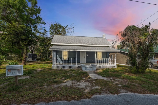 bungalow featuring covered porch and roof with shingles