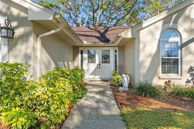 property entrance with roof with shingles and stucco siding