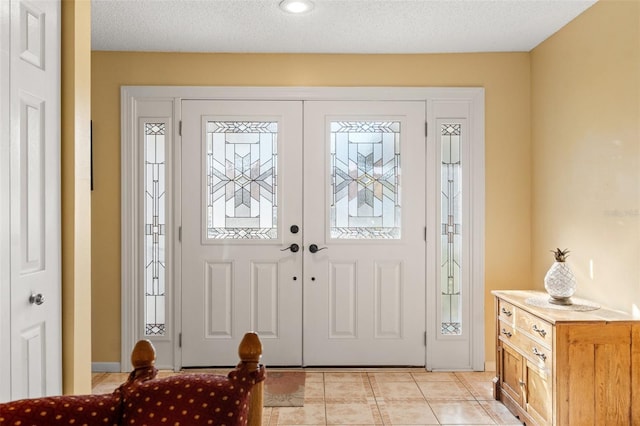 foyer entrance with light tile patterned floors and a textured ceiling