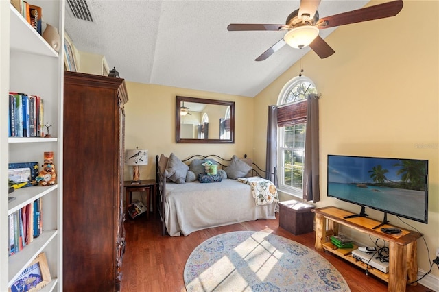 bedroom featuring lofted ceiling, a textured ceiling, wood finished floors, and visible vents