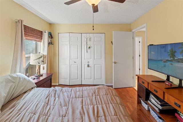 bedroom with a textured ceiling, ceiling fan, wood finished floors, baseboards, and a closet