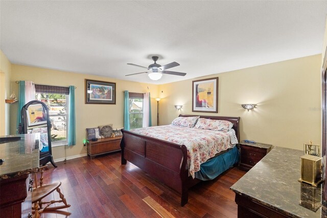 bedroom with dark wood-style floors, ceiling fan, multiple windows, and baseboards