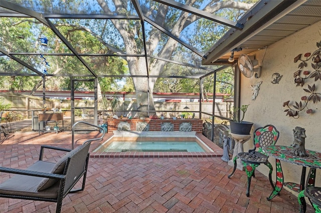 view of patio featuring an in ground hot tub, fence, and glass enclosure