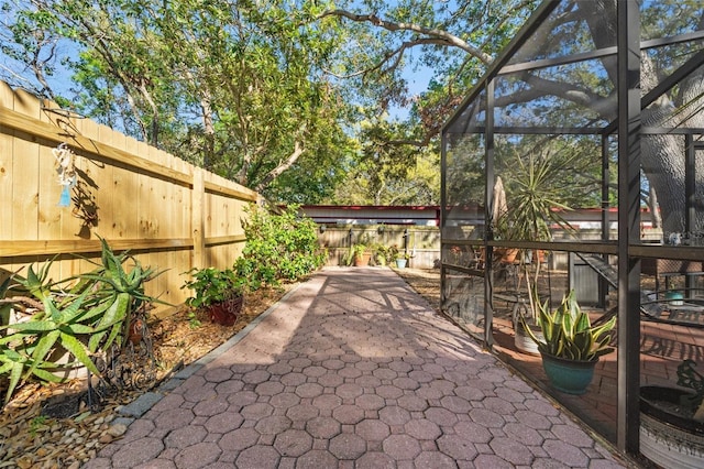 view of patio featuring glass enclosure and a fenced backyard