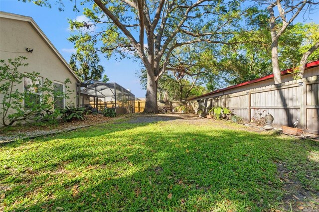 view of yard with glass enclosure and a fenced backyard