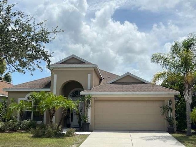 view of front facade with a garage, driveway, and stucco siding