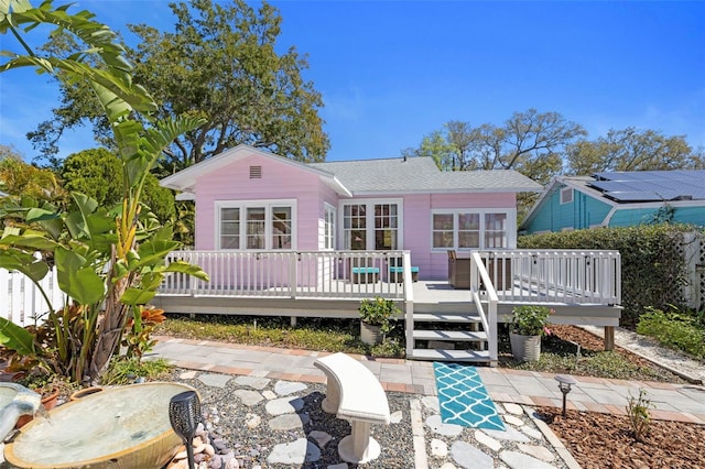 rear view of property featuring roof with shingles and a deck