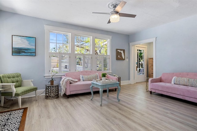 living room featuring a ceiling fan, light wood-type flooring, and baseboards