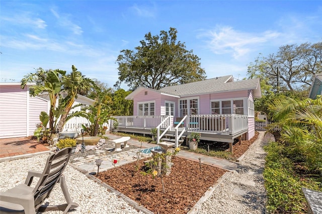 back of house featuring a deck, a shingled roof, a patio area, and a sunroom