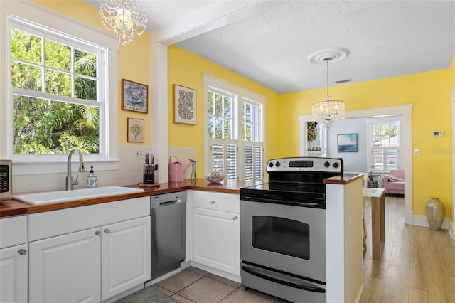 kitchen featuring a chandelier, a peninsula, a sink, white cabinetry, and appliances with stainless steel finishes