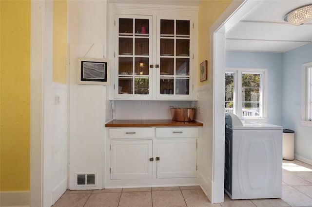 interior space featuring light tile patterned floors, visible vents, washer / dryer, laundry area, and baseboards