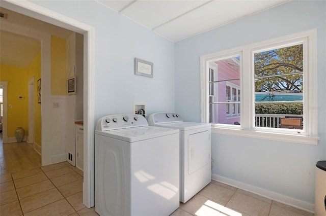 washroom featuring light tile patterned floors, baseboards, visible vents, and washing machine and clothes dryer