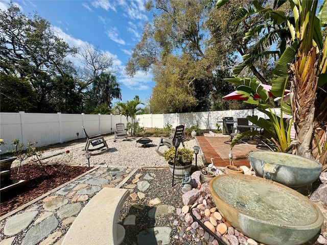 view of yard with an outdoor fire pit, a fenced backyard, and a patio