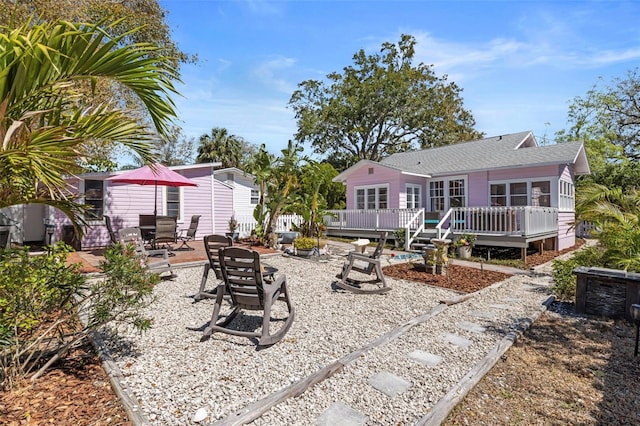 back of property with a patio area, roof with shingles, a fire pit, and a wooden deck