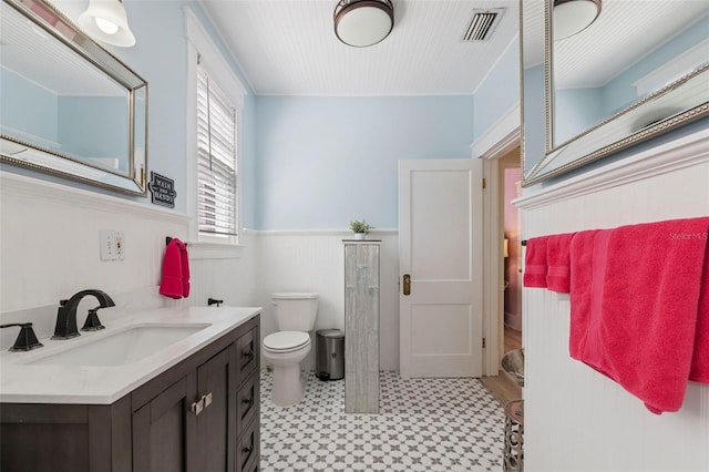 bathroom with wainscoting, visible vents, vanity, and toilet