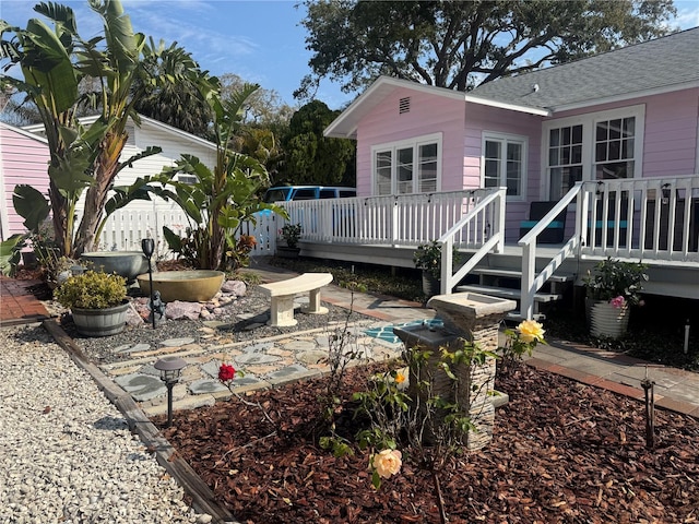 back of property featuring a shingled roof and a deck