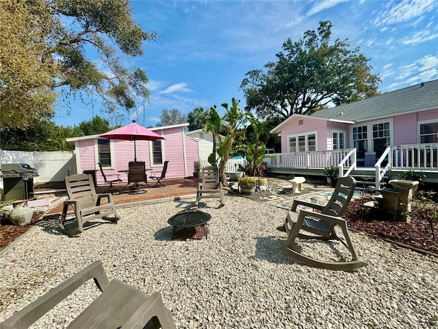 view of yard with an outdoor fire pit, fence, and a deck