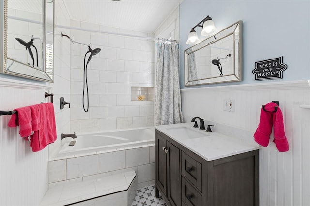 bathroom featuring tiled shower / bath, a wainscoted wall, and vanity