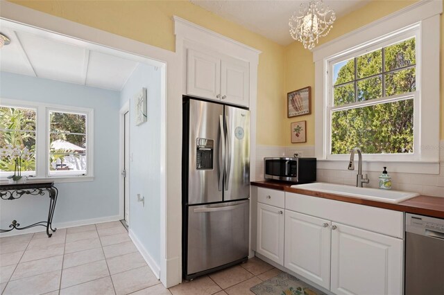 kitchen featuring a wealth of natural light, light tile patterned floors, stainless steel appliances, and a sink