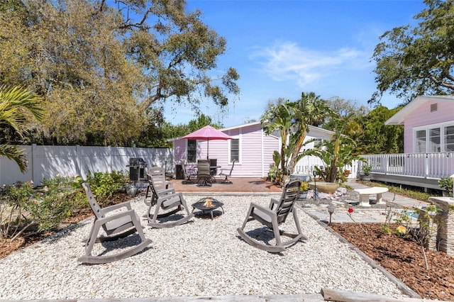 exterior space featuring a wooden deck, fence, a fire pit, and a patio