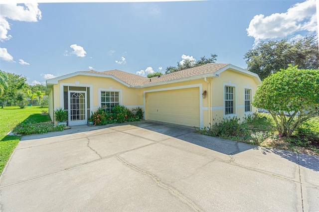 ranch-style house featuring a shingled roof, concrete driveway, an attached garage, a front lawn, and stucco siding