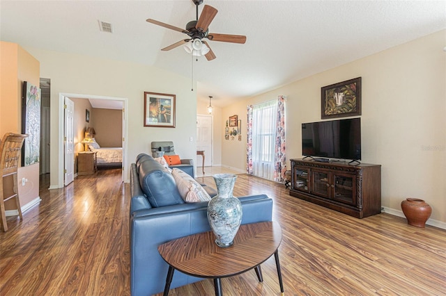 living area featuring visible vents, ceiling fan, vaulted ceiling, wood finished floors, and baseboards