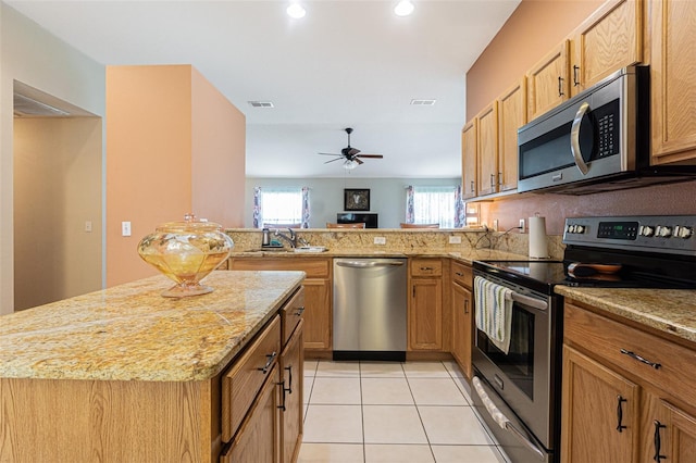 kitchen featuring light tile patterned flooring, stainless steel appliances, a peninsula, a sink, and visible vents