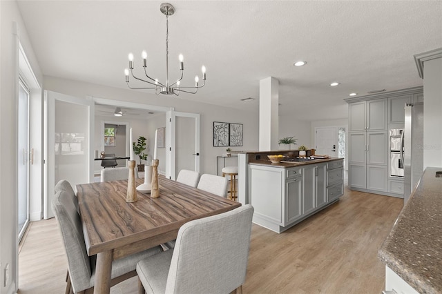 dining room with recessed lighting, light wood-style floors, and a textured ceiling