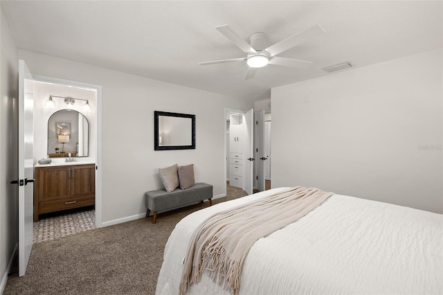 carpeted bedroom with visible vents, connected bathroom, baseboards, and a sink