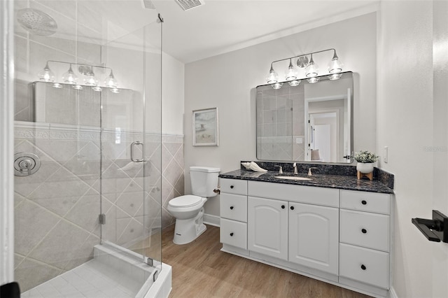 bathroom with vanity, wood finished floors, baseboards, a shower stall, and toilet