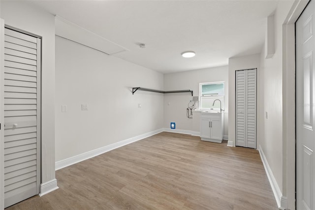 laundry room with baseboards, light wood finished floors, and a sink