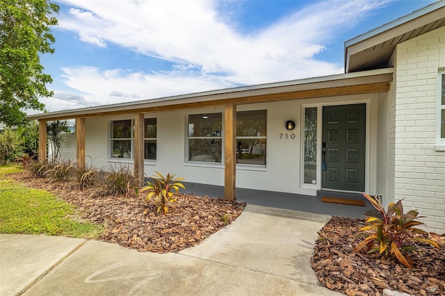 entrance to property with a porch and brick siding