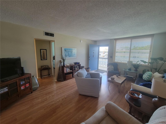 living area featuring a textured ceiling, wood finished floors, and visible vents