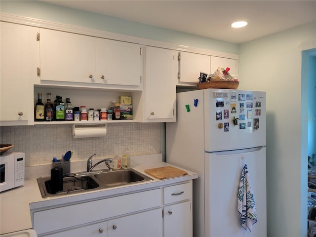 kitchen featuring a sink, white appliances, light countertops, and backsplash