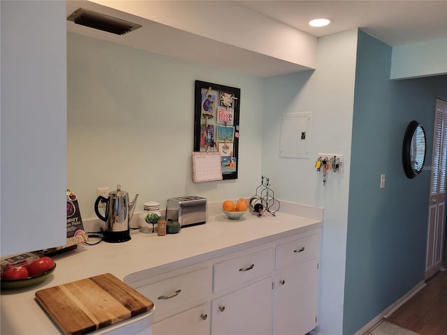 kitchen with light countertops, electric panel, visible vents, and white cabinetry