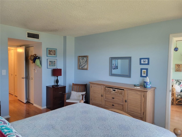 bedroom featuring a textured ceiling, wood finished floors, and visible vents