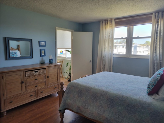 bedroom with a textured ceiling and dark wood finished floors