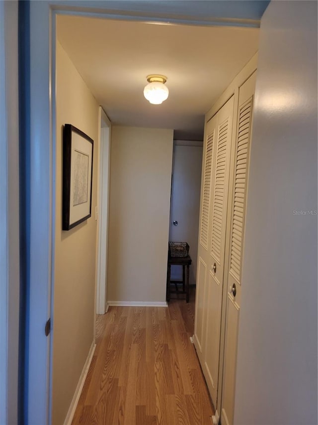 hall featuring light wood-style flooring and baseboards