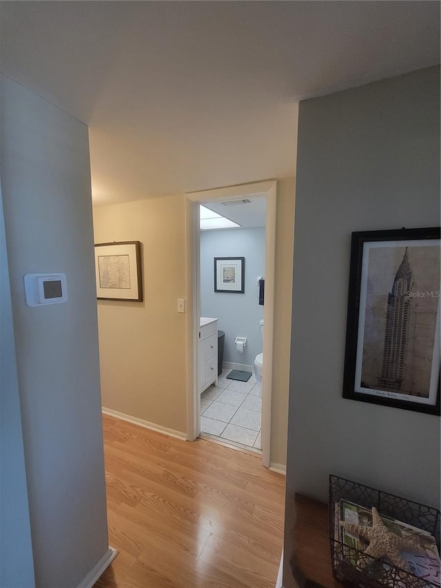 corridor with light wood-style flooring and baseboards