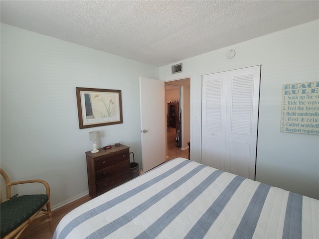 bedroom featuring a closet, visible vents, a textured ceiling, and baseboards