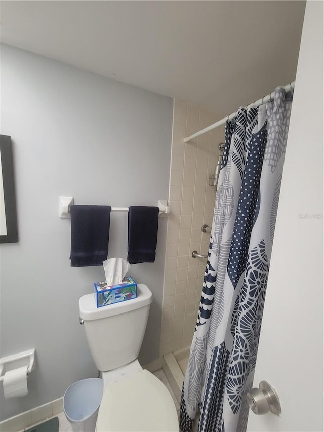 full bathroom with a tile shower and toilet