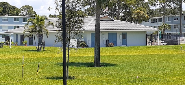 view of front of property with fence, a tiled roof, a front lawn, and stucco siding