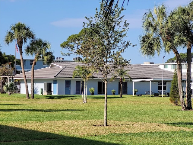 view of front of house featuring a tiled roof, a front lawn, and stucco siding