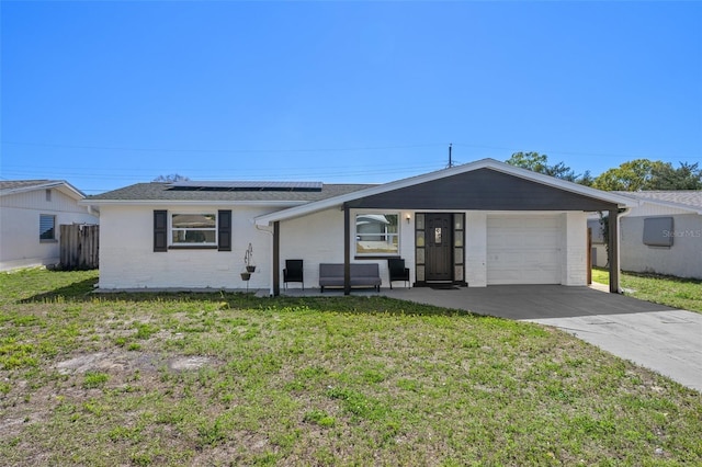 ranch-style house featuring solar panels, an attached garage, concrete driveway, and a front yard