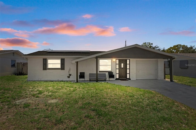 single story home with a lawn, roof mounted solar panels, fence, concrete driveway, and a garage