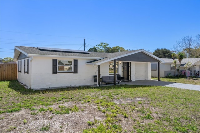 ranch-style house with fence, driveway, solar panels, a front lawn, and a garage